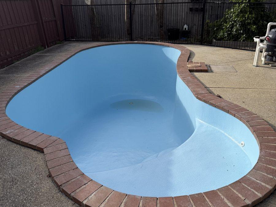 Empty kidney-shaped fibreglass pool after resurfacing